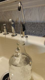 A filter faucet with water running into a glass jug