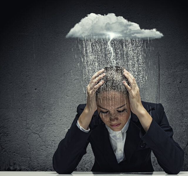 Young woman crying with raincloud over her head.