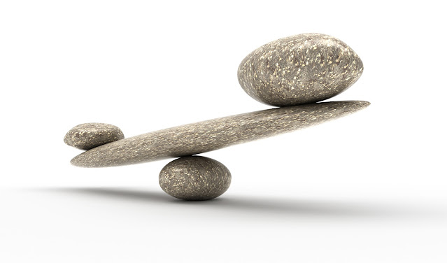 2 stones on the ends of a stone fulcrum, illustrating balance.