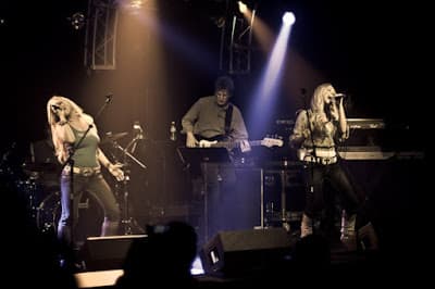 Two girls singing with a guitar player