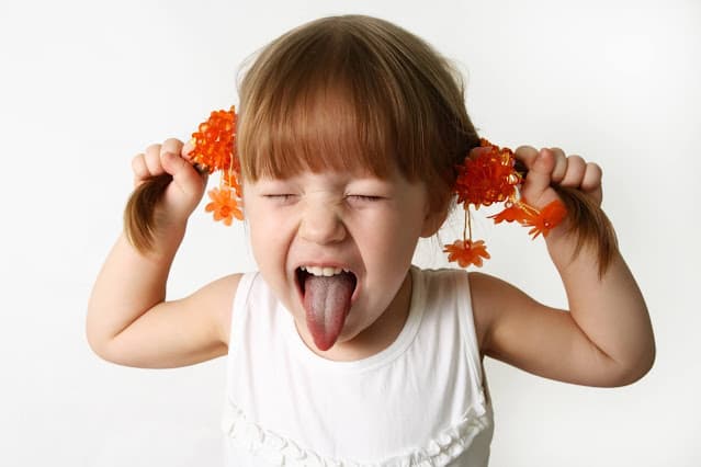 Little girl sticking tongue out and pulling her pigtails sideways