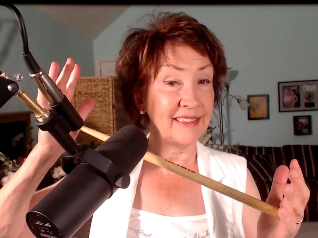 Demonstrating holding a drumstick between palms to increase vocal control.