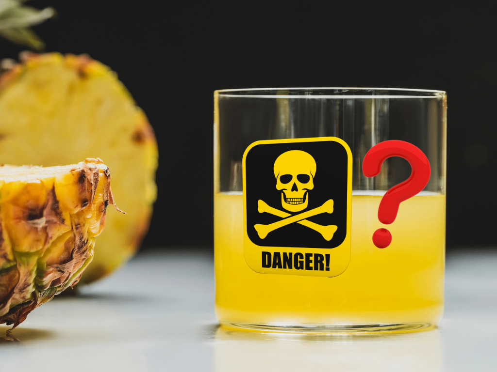 Glass of pineapple juice with danger sign and question mark next to a cut pineapple 