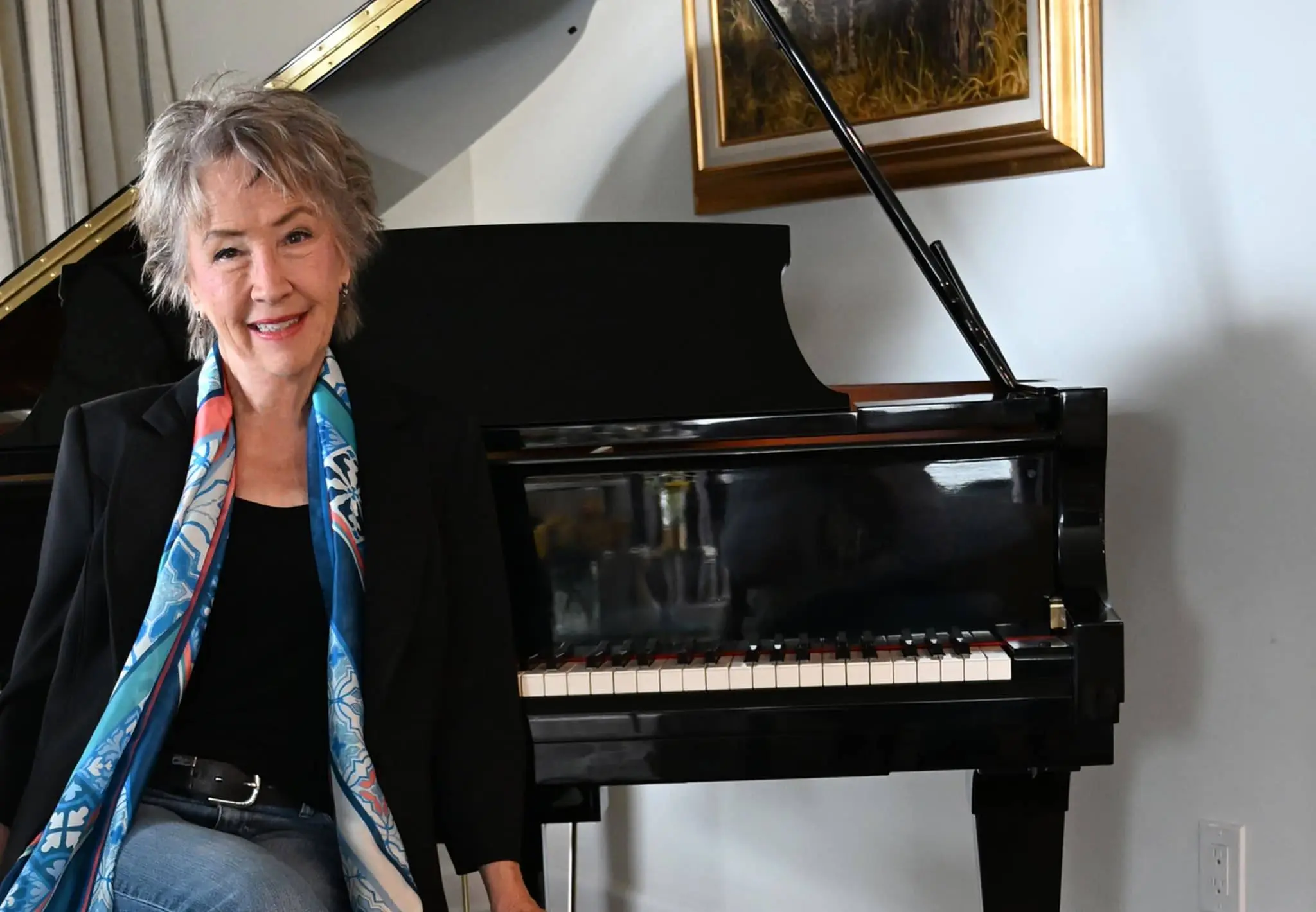 Judy Rodman sitting in front of a baby grand piano